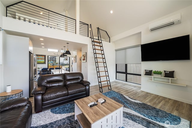 living area featuring recessed lighting, wood finished floors, a towering ceiling, stairway, and a wall mounted air conditioner