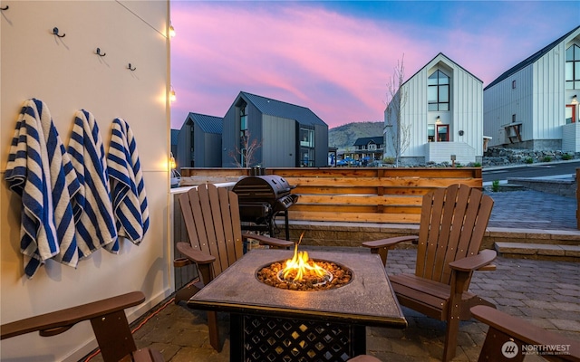 patio terrace at dusk featuring a fire pit and area for grilling