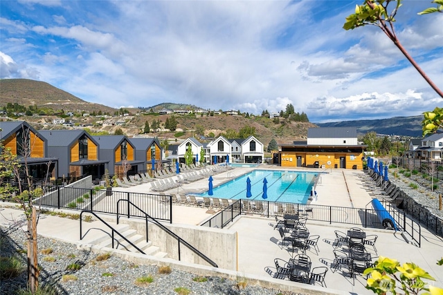 pool with a residential view, fence, a mountain view, and a patio