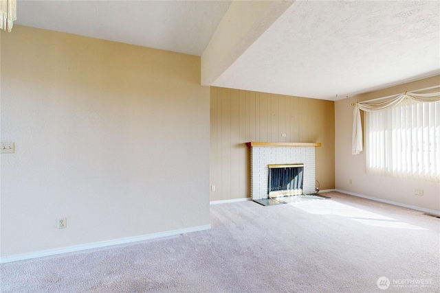 unfurnished living room featuring light carpet, a textured ceiling, a brick fireplace, and baseboards