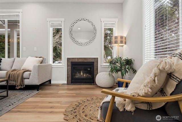 sitting room featuring baseboards, a tiled fireplace, and wood finished floors