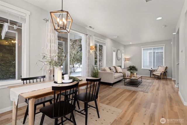 dining room featuring visible vents, a notable chandelier, baseboards, and wood finished floors