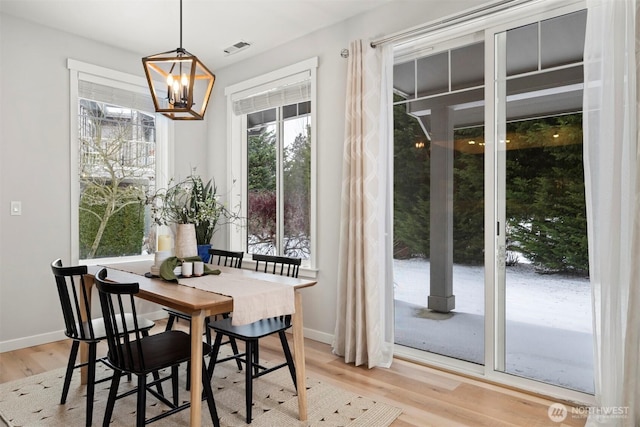 dining space featuring light wood-type flooring, visible vents, a notable chandelier, and baseboards