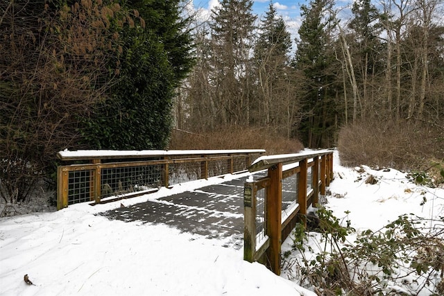 snow covered deck with a forest view