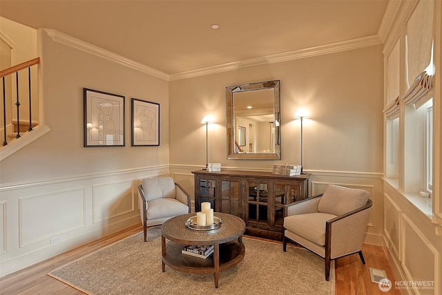 sitting room with ornamental molding, stairway, and wood finished floors