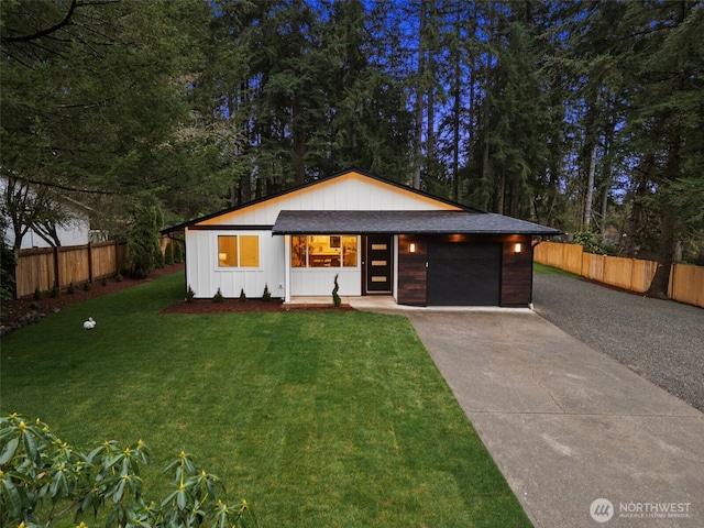 view of front of home featuring a garage, concrete driveway, a front lawn, and fence