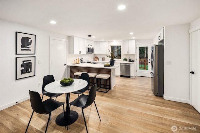 dining space with light wood-style flooring, recessed lighting, and baseboards