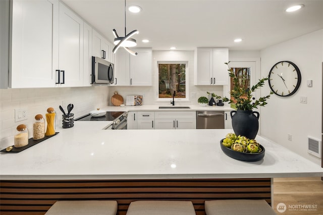 kitchen featuring a breakfast bar, a sink, stainless steel appliances, light countertops, and backsplash