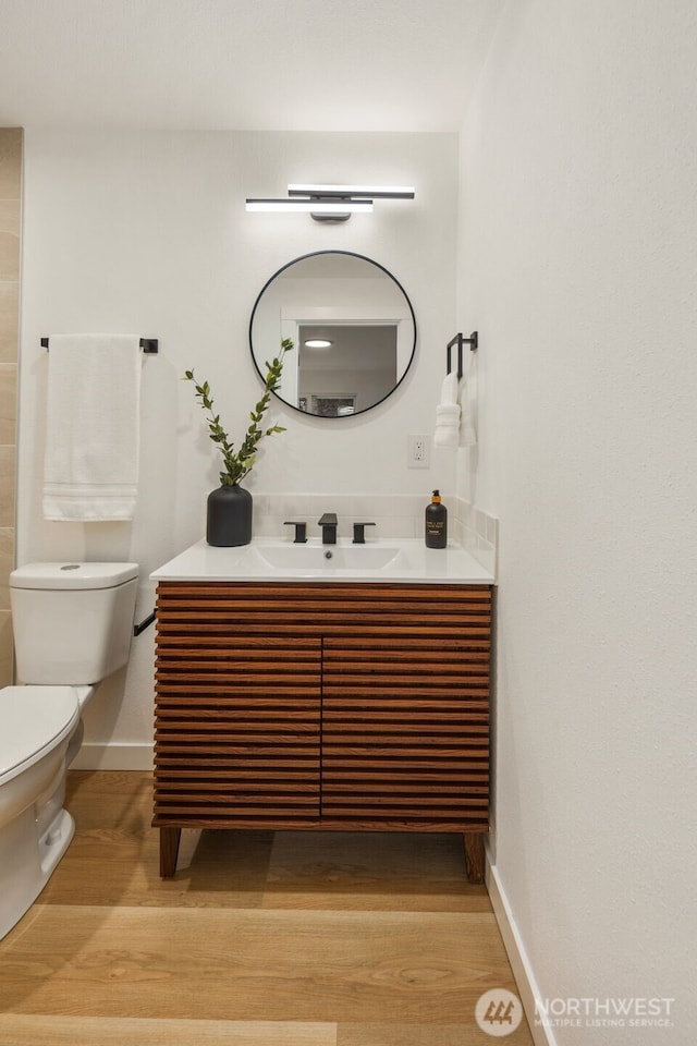 bathroom featuring vanity, toilet, wood finished floors, and baseboards