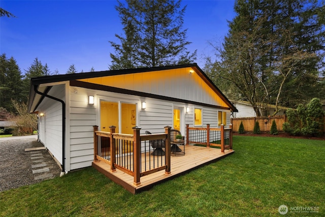 back of house with a wooden deck, a yard, and fence