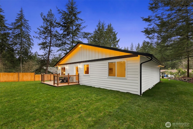 back of property with a lawn, a deck, and fence