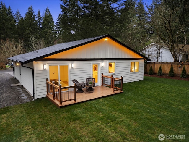 back of property featuring a lawn, a wooden deck, and fence