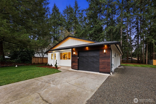 view of front of house featuring driveway, an attached garage, a front yard, and fence