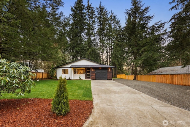 view of front of property featuring a garage, concrete driveway, a front lawn, and fence