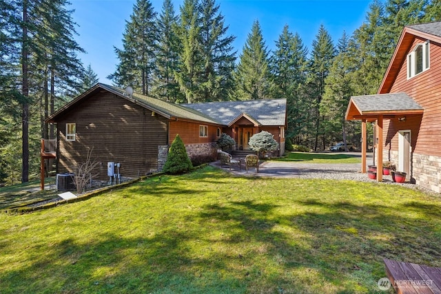 exterior space featuring stone siding, a front yard, and cooling unit