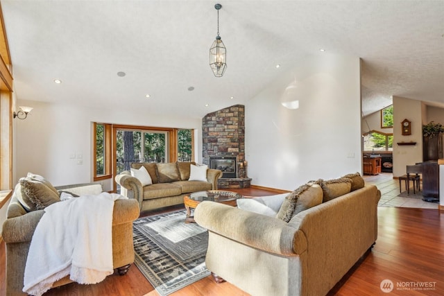 living area featuring a large fireplace, high vaulted ceiling, wood finished floors, and recessed lighting