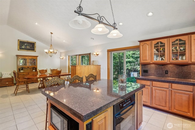 kitchen featuring glass insert cabinets, light tile patterned flooring, vaulted ceiling, and tile countertops