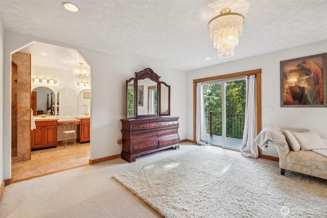 bedroom featuring arched walkways, access to outside, a notable chandelier, and ensuite bath