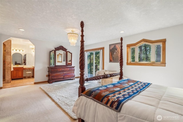 bedroom featuring arched walkways, light colored carpet, a textured ceiling, ensuite bath, and baseboards