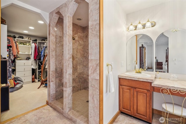 bathroom featuring recessed lighting, a spacious closet, vanity, tiled shower, and baseboards