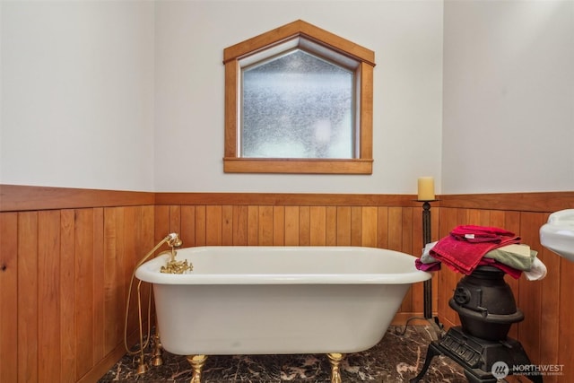 full bath featuring a soaking tub, wooden walls, and wainscoting