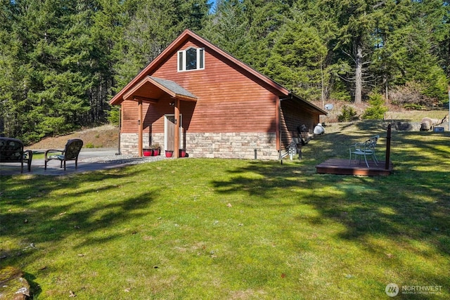 view of property exterior featuring a forest view, stone siding, and a lawn