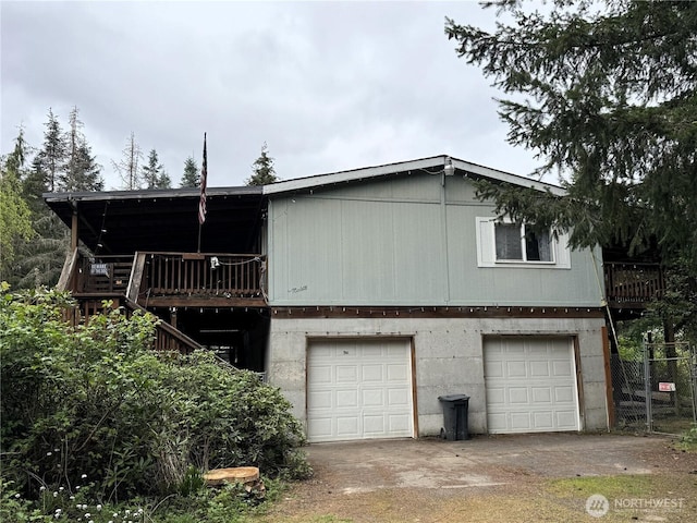 rear view of house with a garage, concrete driveway, and a deck
