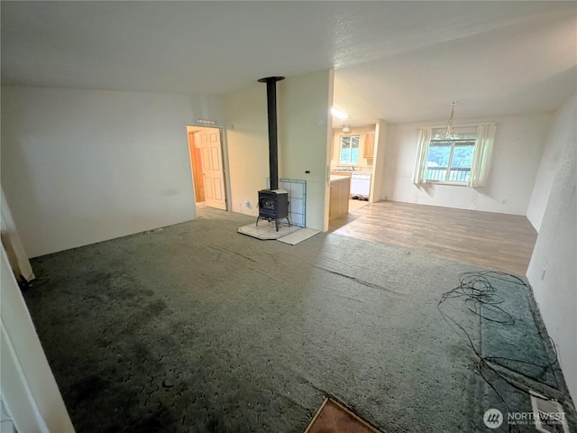 unfurnished living room with a wood stove and carpet flooring