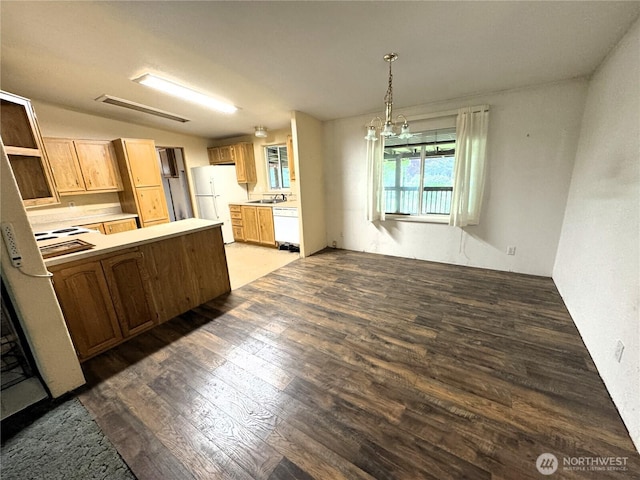 kitchen with white appliances, a peninsula, hanging light fixtures, and wood finished floors