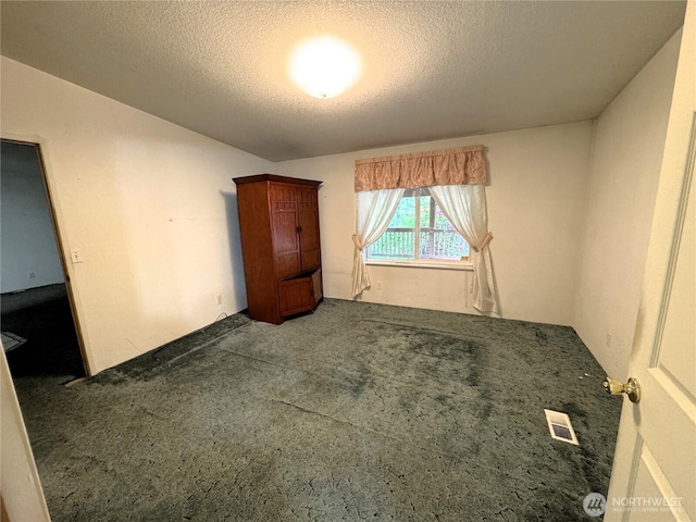 unfurnished bedroom featuring carpet floors, a textured ceiling, and visible vents