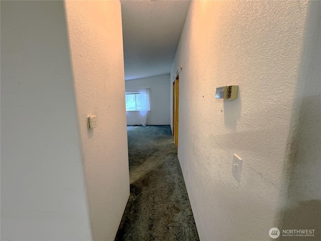 corridor featuring carpet floors and a textured wall