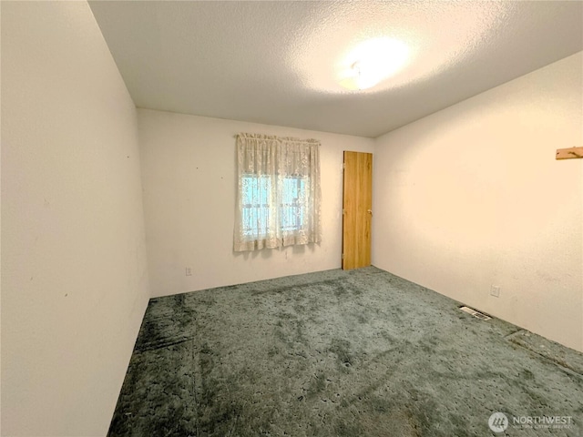 carpeted empty room with a textured ceiling