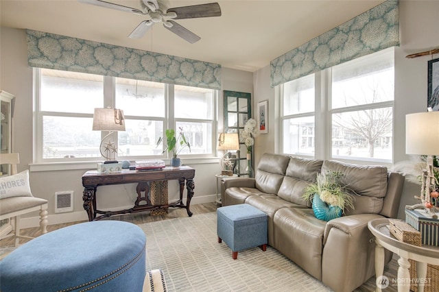 living area with a ceiling fan, baseboards, visible vents, and wood finished floors