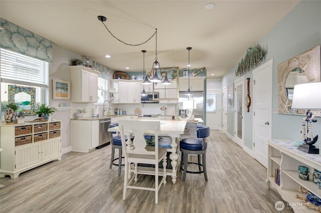 kitchen featuring light wood finished floors, appliances with stainless steel finishes, light countertops, and a breakfast bar area