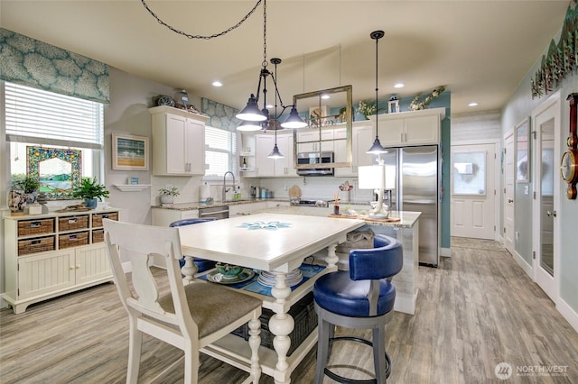 kitchen featuring light wood finished floors, light countertops, appliances with stainless steel finishes, and a sink