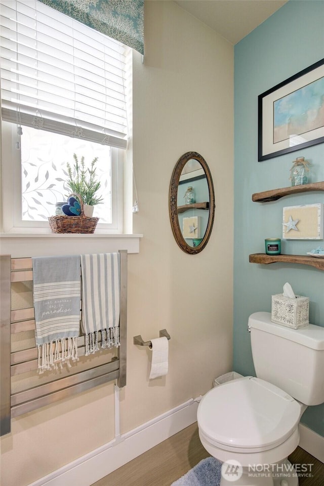 half bath featuring toilet, baseboards, and wood finished floors