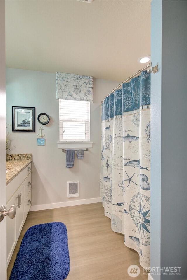 bathroom with curtained shower, vanity, baseboards, and wood finished floors