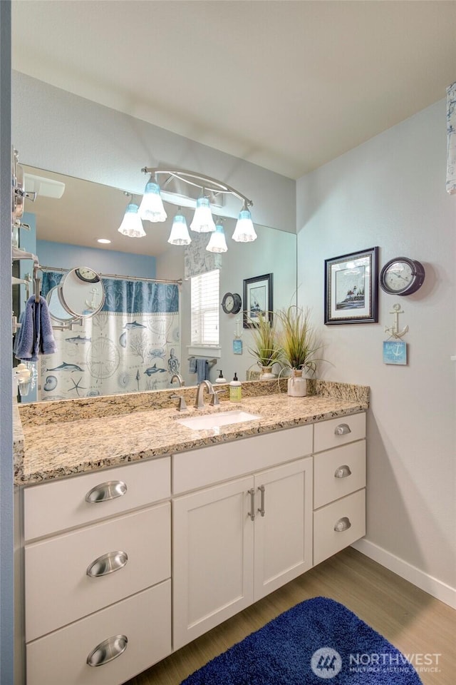 full bathroom with curtained shower, wood finished floors, vanity, and baseboards