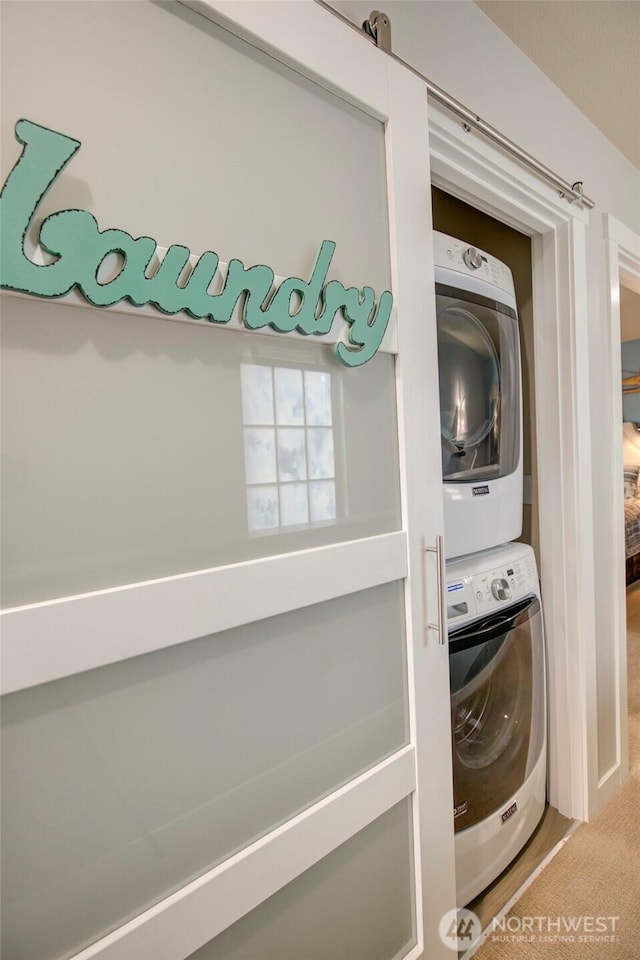 laundry area featuring laundry area, stacked washer and dryer, and carpet flooring