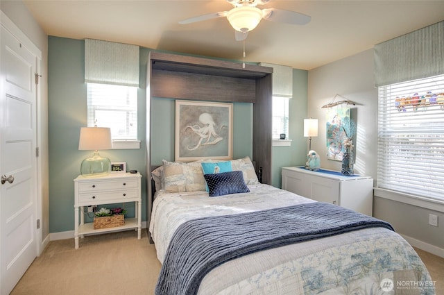 bedroom with a ceiling fan, light carpet, and baseboards