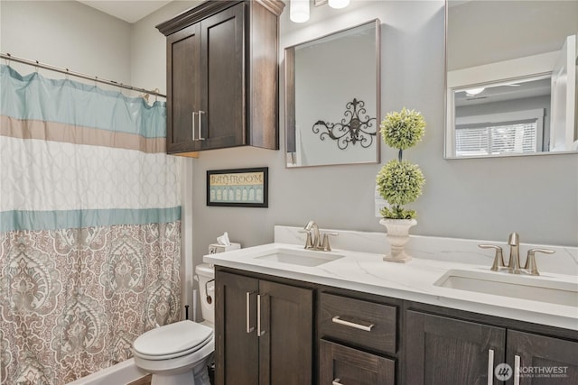 full bathroom featuring double vanity, a shower with shower curtain, a sink, and toilet