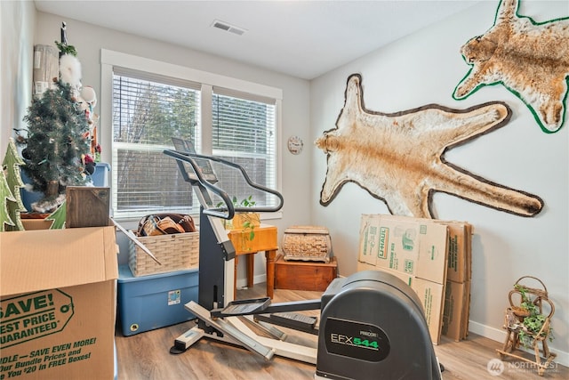 workout area with baseboards, visible vents, and wood finished floors