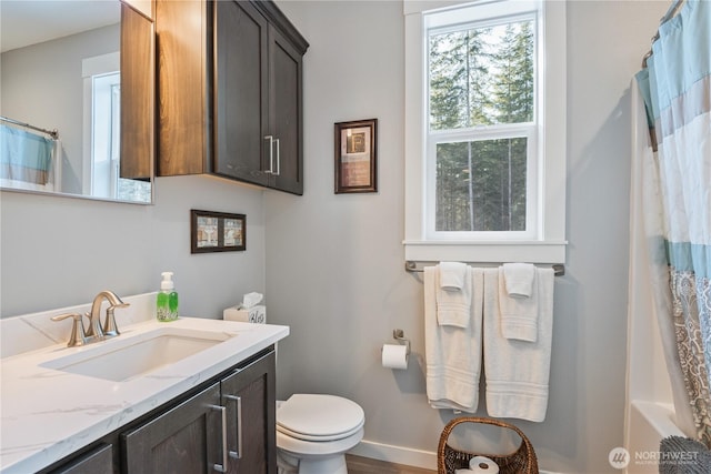 bathroom with curtained shower, vanity, toilet, and baseboards