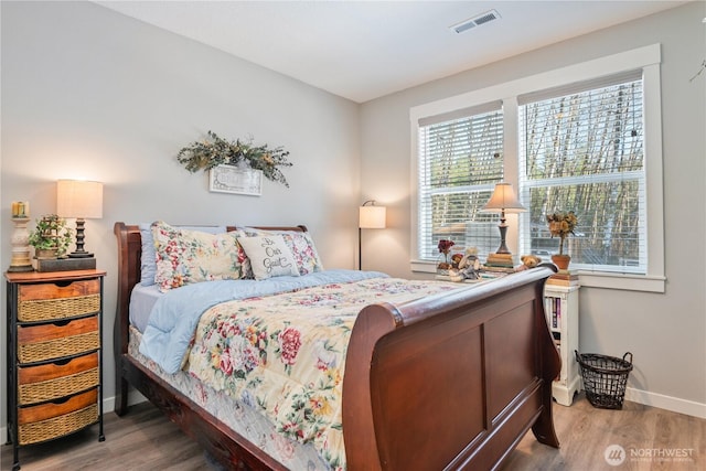 bedroom featuring visible vents, baseboards, and wood finished floors