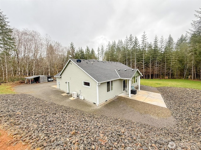 view of side of home with crawl space, a shingled roof, and a lawn