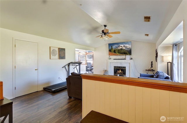 living room featuring ceiling fan, a fireplace, vaulted ceiling, and dark wood finished floors