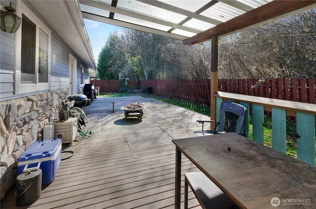 wooden terrace featuring a fenced backyard, a fire pit, and outdoor dining space