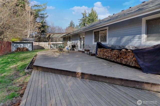 deck with a yard, a fenced backyard, a shed, and an outbuilding