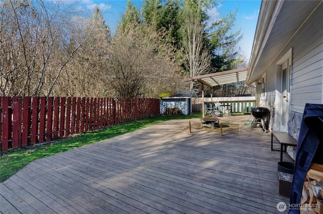 deck with a grill, a fenced backyard, an outdoor structure, and a storage unit