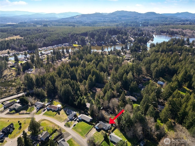 drone / aerial view with a wooded view and a water and mountain view